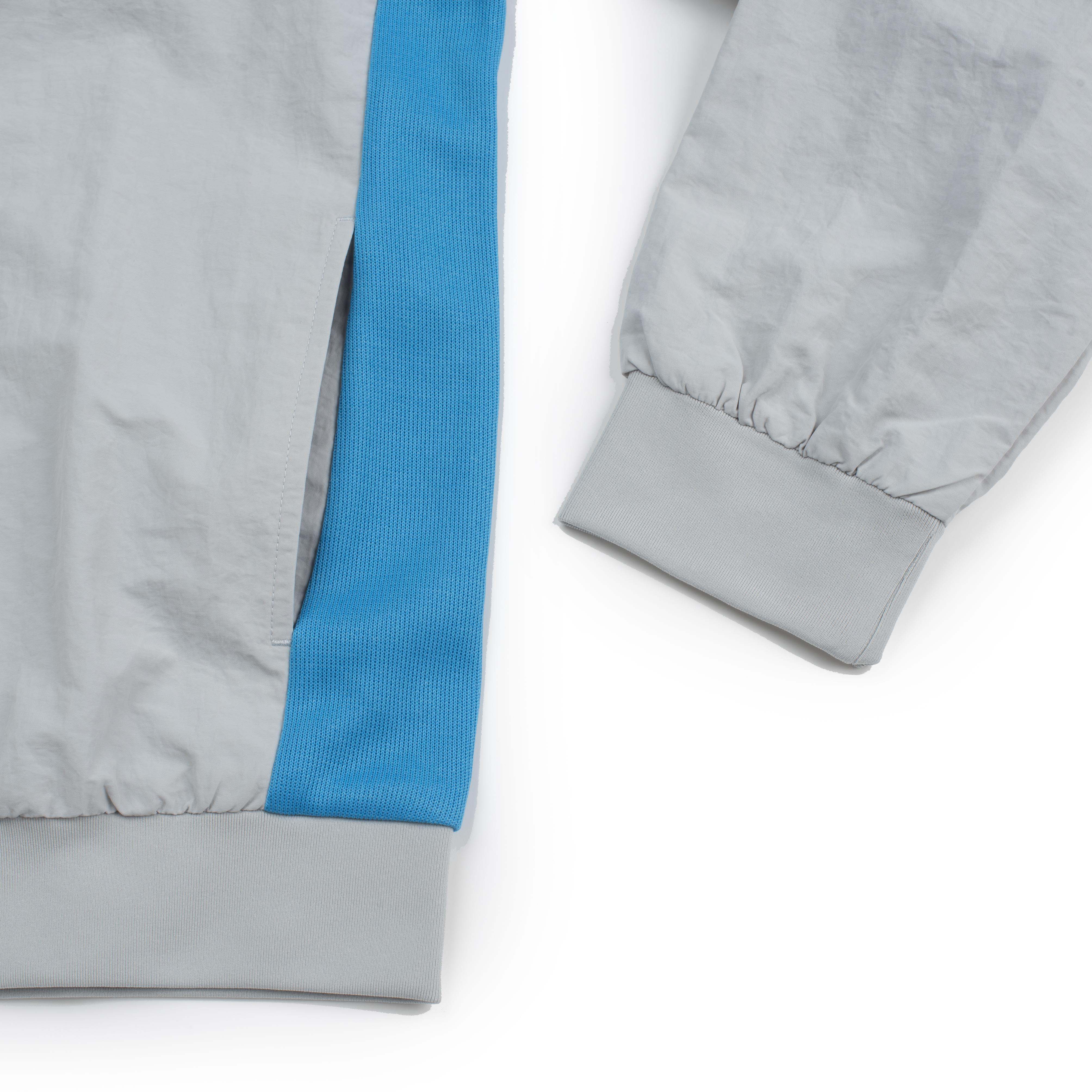 Jaqueta masculina New Balance Grêmio 2026 vista frontal em cinza e azul celeste